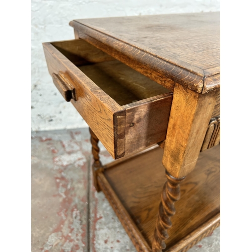 74 - A carved oak two tier side table on barley twist supports