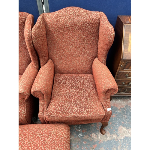 99 - A pair of Victorian style red floral fabric upholstered wingback armchairs with cabriole supports an... 