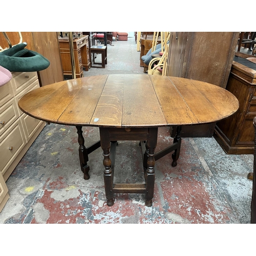 151 - A Georgian oak drop leaf gate leg oval dining table - approx. 74cm high x 109cm wide x 153cm long