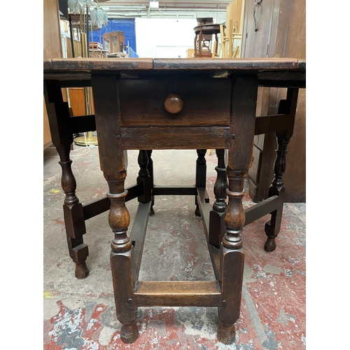 151 - A Georgian oak drop leaf gate leg oval dining table - approx. 74cm high x 109cm wide x 153cm long