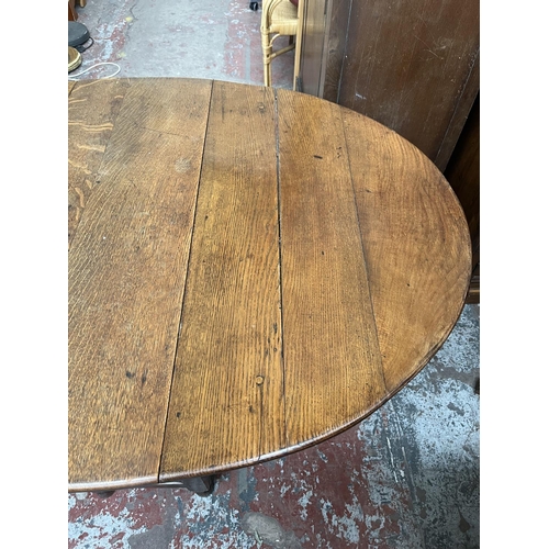 151 - A Georgian oak drop leaf gate leg oval dining table - approx. 74cm high x 109cm wide x 153cm long