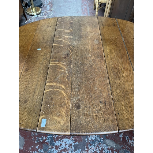 151 - A Georgian oak drop leaf gate leg oval dining table - approx. 74cm high x 109cm wide x 153cm long