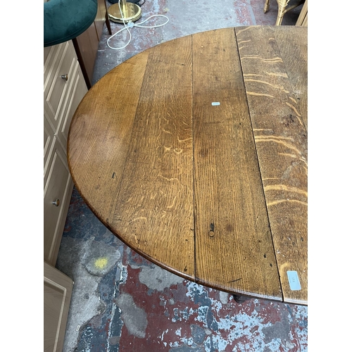 151 - A Georgian oak drop leaf gate leg oval dining table - approx. 74cm high x 109cm wide x 153cm long