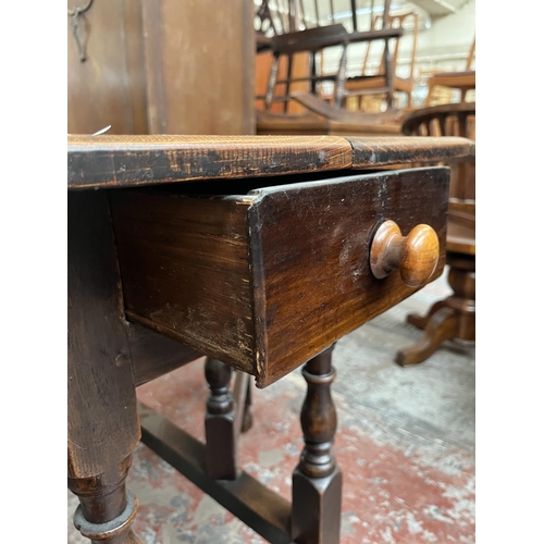 151 - A Georgian oak drop leaf gate leg oval dining table - approx. 74cm high x 109cm wide x 153cm long