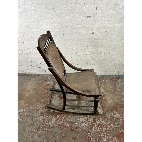 47 - An early 20th century beech rocking chair with spindle back and shell design