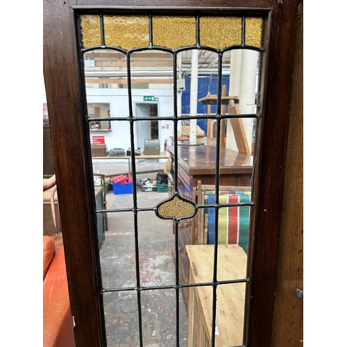 217 - An Arts & Crafts oak bookcase with two leaded and stained glass doors and copper hinges - approx. 19... 