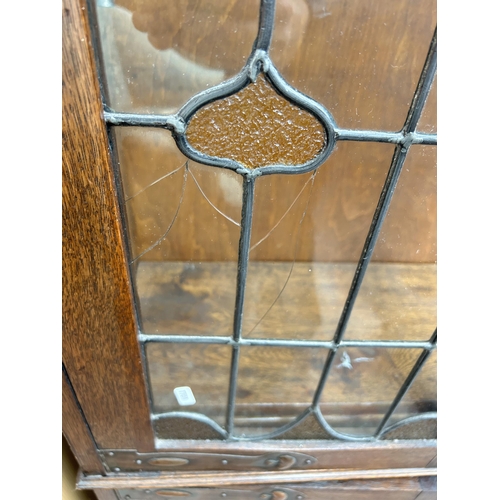 217 - An Arts & Crafts oak bookcase with two leaded and stained glass doors and copper hinges - approx. 19... 