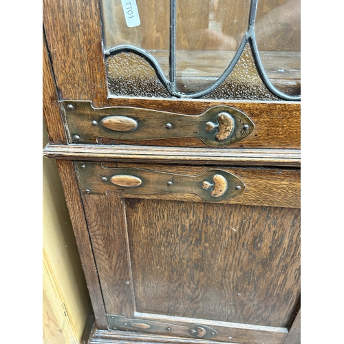 217 - An Arts & Crafts oak bookcase with two leaded and stained glass doors and copper hinges - approx. 19... 