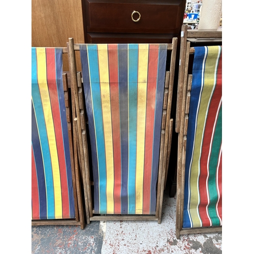 219 - Three mid 20th century beech and multicoloured fabric folding deck chairs