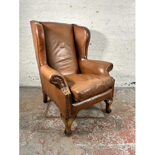 242 - A tan leather wing back armchair with cabriole supports