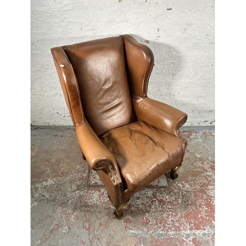 242 - A tan leather wing back armchair with cabriole supports