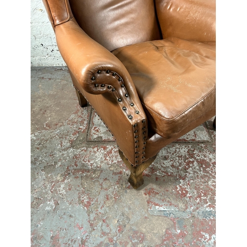 242 - A tan leather wing back armchair with cabriole supports