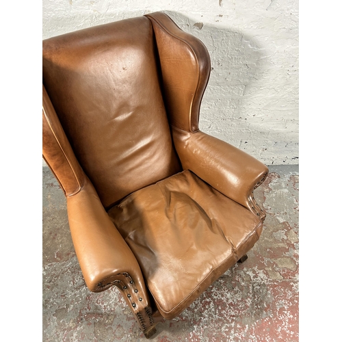 242 - A tan leather wing back armchair with cabriole supports