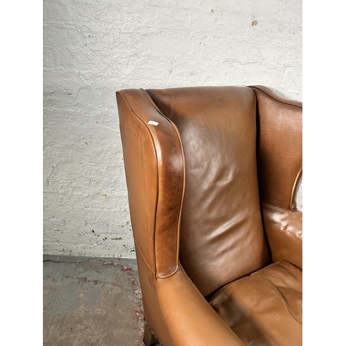 242 - A tan leather wing back armchair with cabriole supports