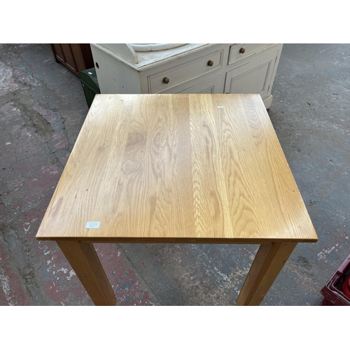 168A - A modern oak square dining table on castors - approx. 80cm high x 77cm wide x 77cm long