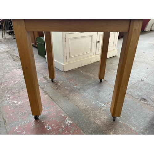 168A - A modern oak square dining table on castors - approx. 80cm high x 77cm wide x 77cm long