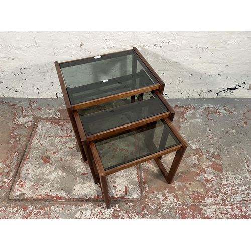 172 - A teak and smoked glass nest of three tables