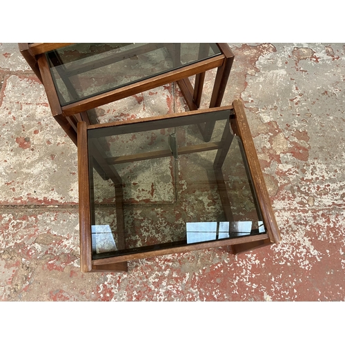 172 - A teak and smoked glass nest of three tables