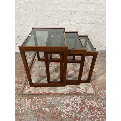 172 - A teak and smoked glass nest of three tables