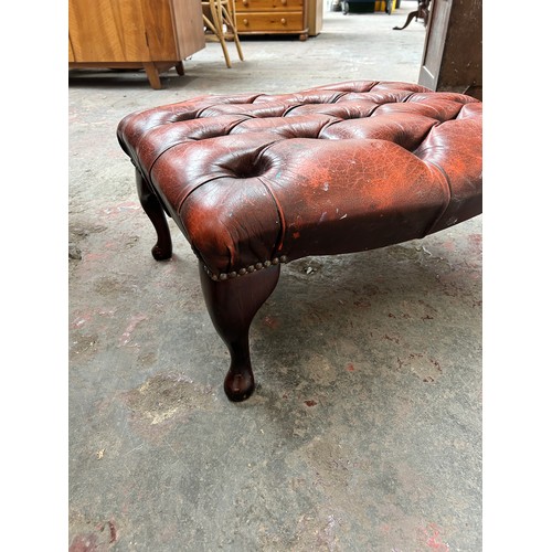 55 - An ox blood red leather Chesterfield footstool on cabriole supports