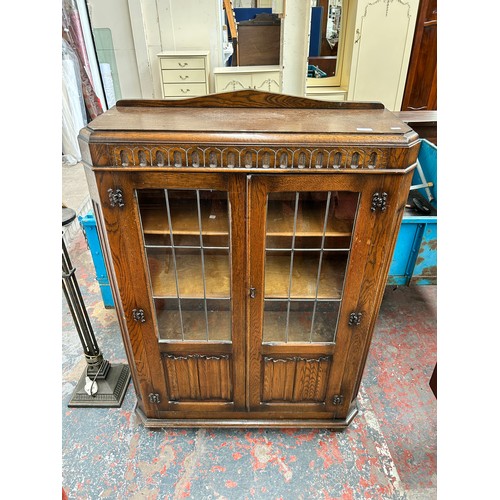 95 - A carved oak linenfold bookcase with two leaded glass doors