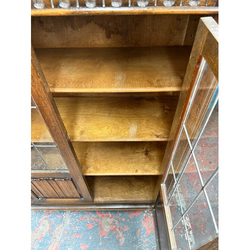 95 - A carved oak linenfold bookcase with two leaded glass doors