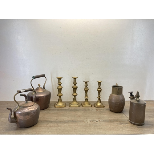 370 - Eight pieces of antique metalware to include two pairs of brass candlesticks, two copper and brass k... 