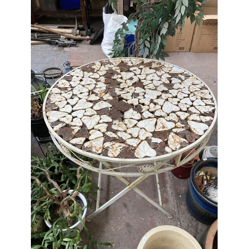 878 - A wrought metal folding patio table with foliate design - approx. 74cm high x 70cm diameter