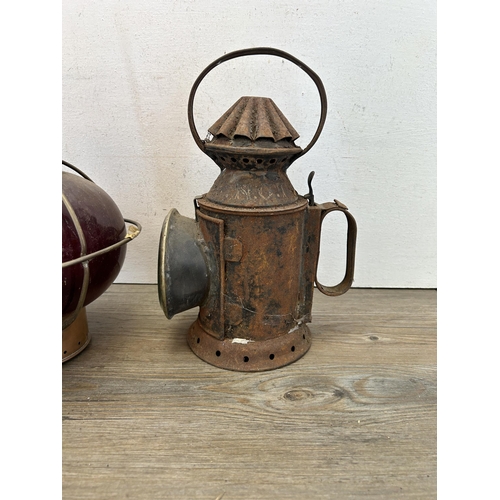 493 - Two vintage lanterns, one copper and red glass nautical onion and one black metal railway - largest ... 