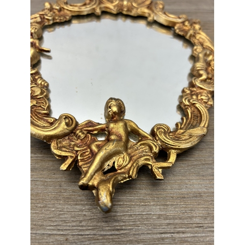 549 - A Rococo style gilt framed wall hanging mirror with cherub and shell design - approx. 26cm high x 19... 