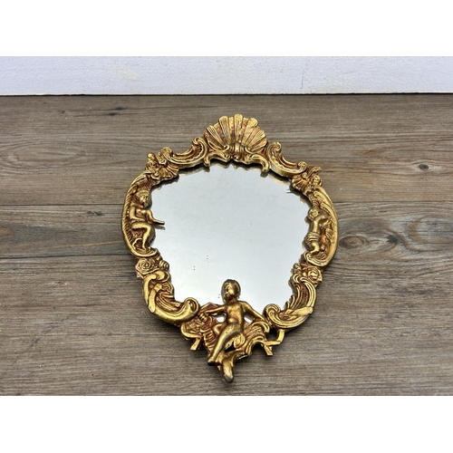 549 - A Rococo style gilt framed wall hanging mirror with cherub and shell design - approx. 26cm high x 19... 