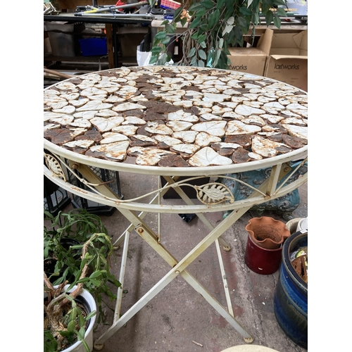 878 - A wrought metal folding patio table with foliate design - approx. 74cm high x 70cm diameter