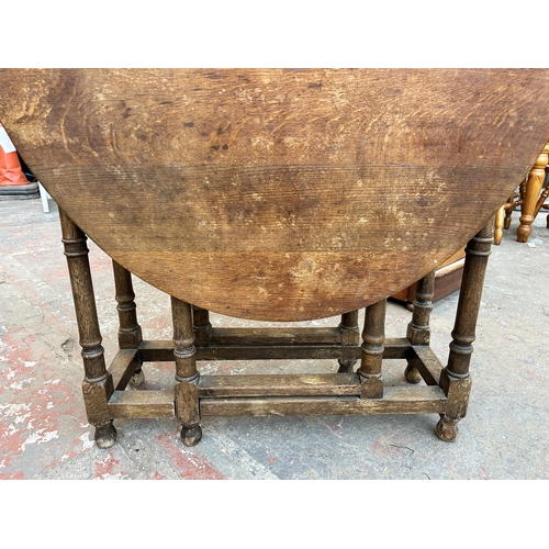 112 - A Georgian oak drop leaf gate leg oval dining table on turned supports