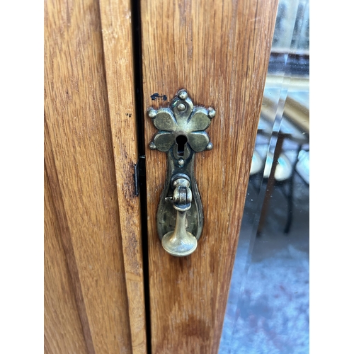 142 - An Edwardian carved oak mirror door wardrobe - approx. 200cm high x 125cm wide x 51cm deep