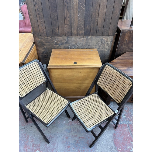 154 - Three pieces of furniture, two ebonised and rattan folding chairs and one Meredew teak cabinet