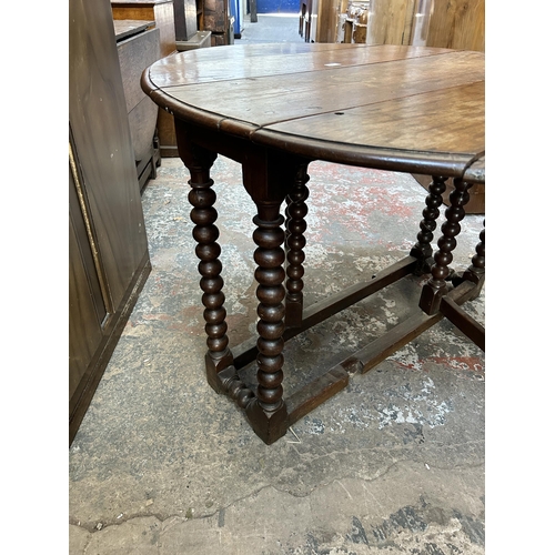 16 - A Georgian oak drop leaf gate leg oval dining table on bobbin turned supports