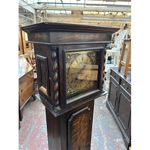 172 - A 1930s oak cased Westminster chime granddaughter clock with brass face, pendulum and key - approx. ... 