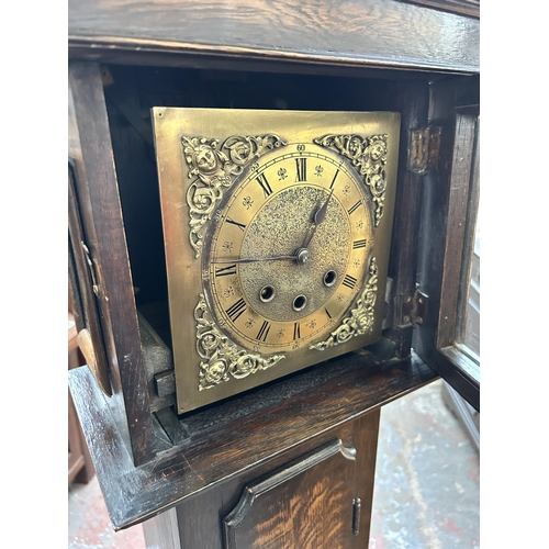 172 - A 1930s oak cased Westminster chime granddaughter clock with brass face, pendulum and key - approx. ... 