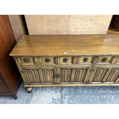 41 - An oak linenfold sideboard on baluster supports - approx. 83cm high x 192cm wide x 49cm deep