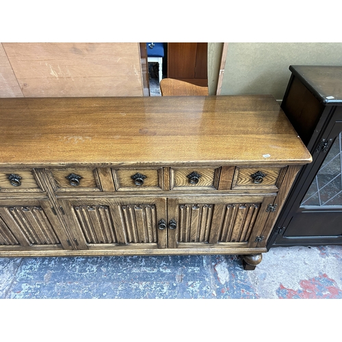 41 - An oak linenfold sideboard on baluster supports - approx. 83cm high x 192cm wide x 49cm deep