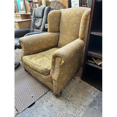 61 - An early 20th century floral upholstered wing back armchair with turned supports and castors