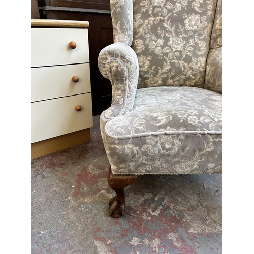 70 - A Georgian style fabric upholstered wing back armchair on ball and claw supports