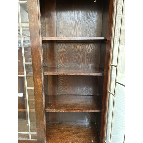 8 - A mid 20th century oak bookcase with three leaded glass doors - approx. 194cm high x 122cm wide x 33... 