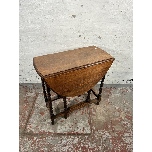 184 - An early 20th century oak drop leaf gate leg oval occasional table on barley twist supports