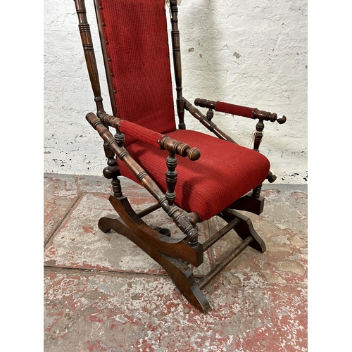 123 - An early 20th century American mahogany and red fabric upholstered rocking chair