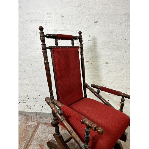 123 - An early 20th century American mahogany and red fabric upholstered rocking chair