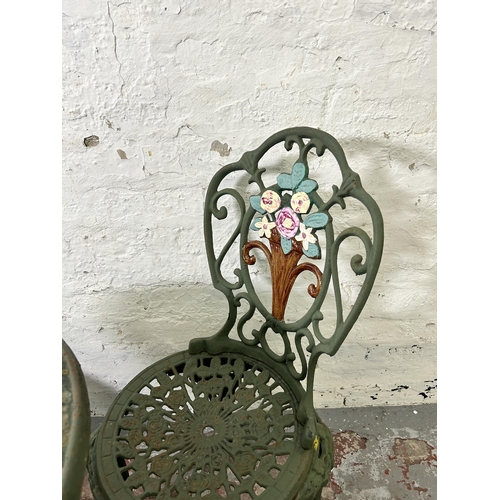 160 - A green painted cast iron patio table and two chairs - approx. 67cm high x 62cm diameter