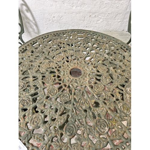 160 - A green painted cast iron patio table and two chairs - approx. 67cm high x 62cm diameter