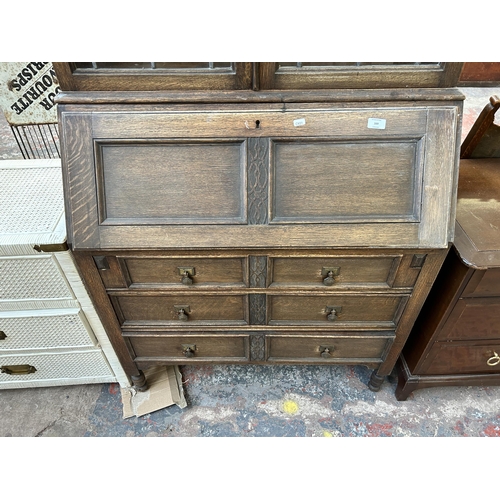 169 - An early 20th century carved oak bureau bookcase with two upper leaded and stained glass doors - app... 