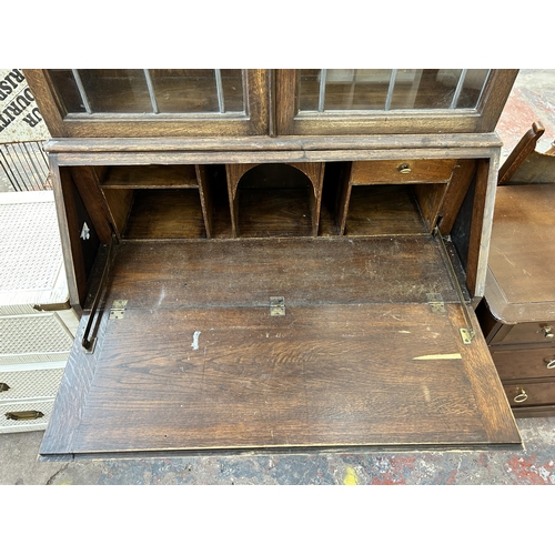 169 - An early 20th century carved oak bureau bookcase with two upper leaded and stained glass doors - app... 